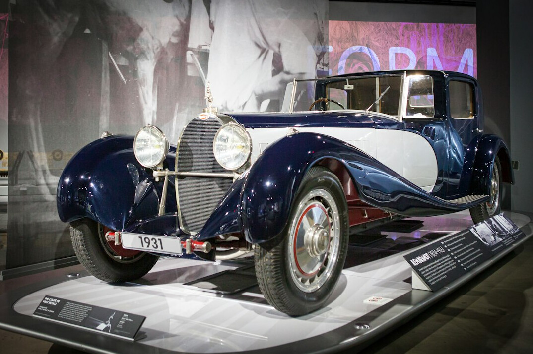 Blue vintage Bugatti automobile on display under dramatic lighting