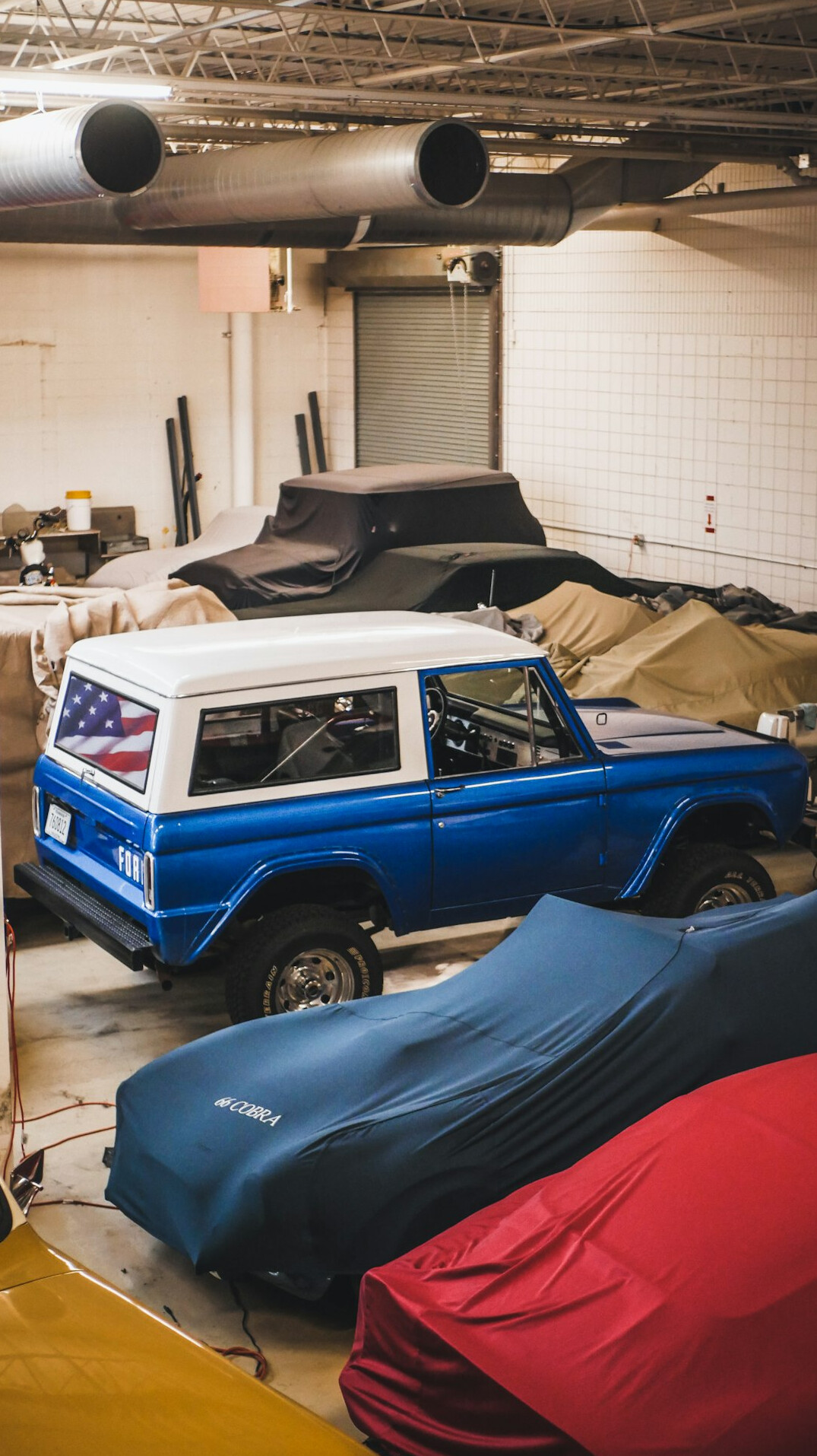 Vertical shot of a private collector's garage with several covered cars