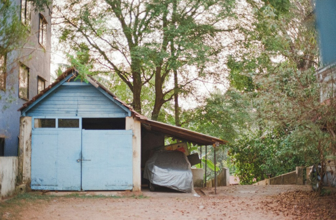 Weathered classic car covered in dust parked in an abandoned shed