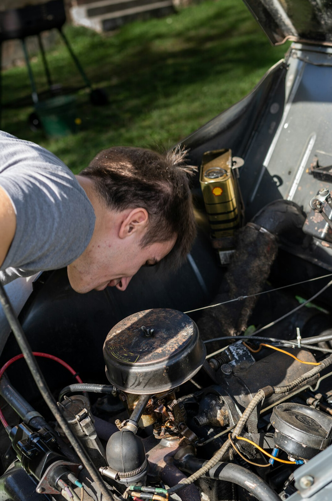 Specialist examining a vintage automobile engine with documentation nearby