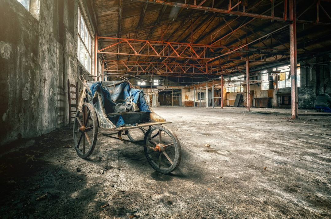 Old forgotten car covered by a dusty tarp in a dim warehouse