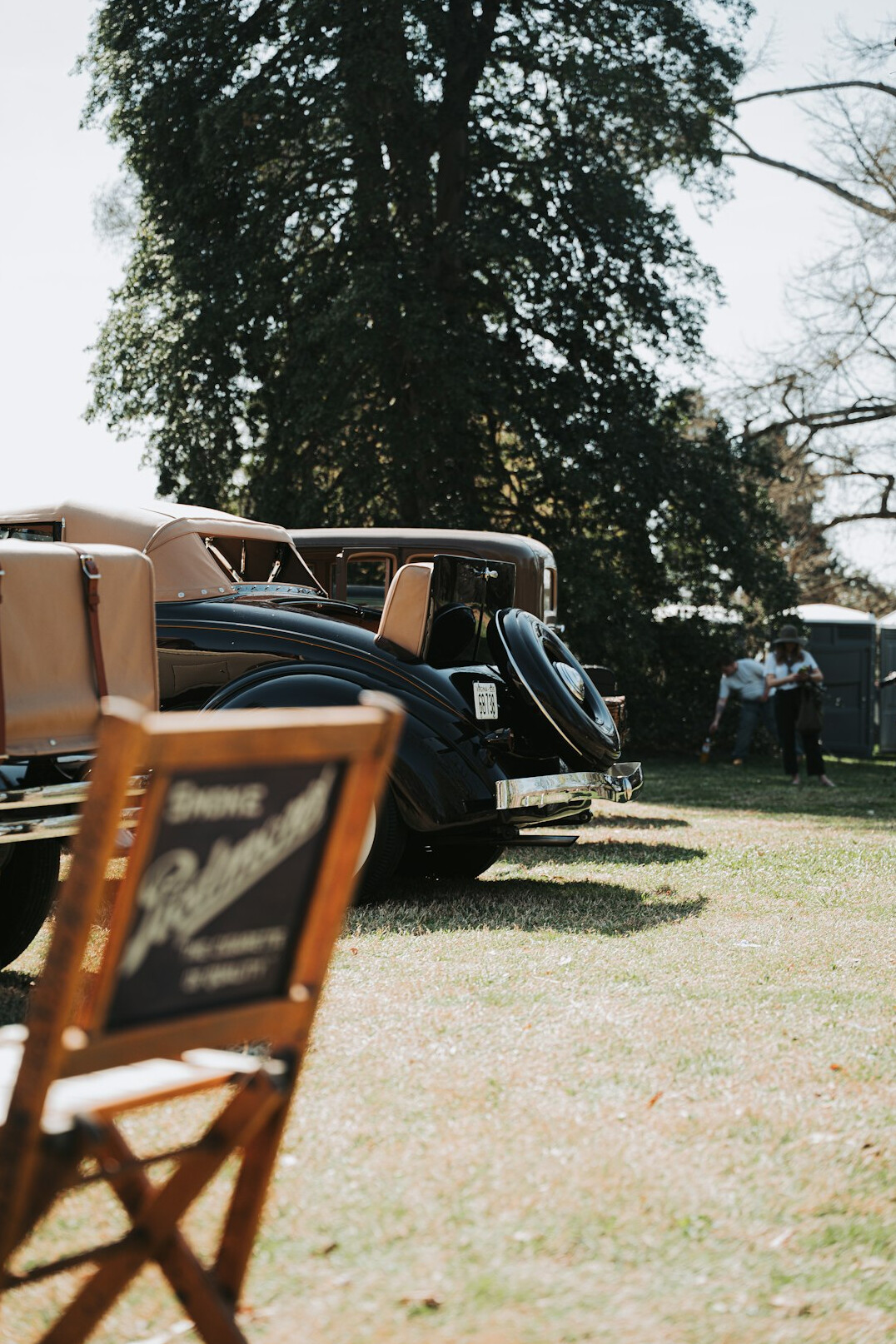 Outdoor automobile festival with tents and classic cars in a green field
